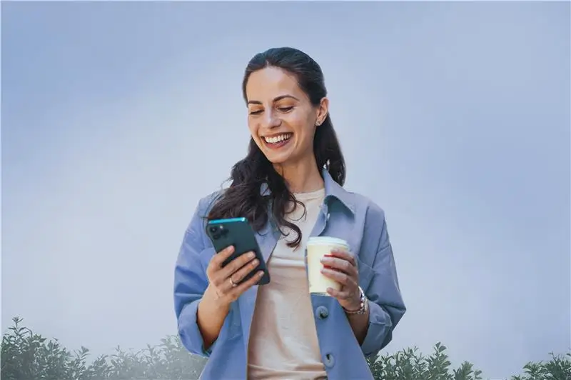 Frau mit Kaffebecher in der Hand nutzt dermanostic am Handy.